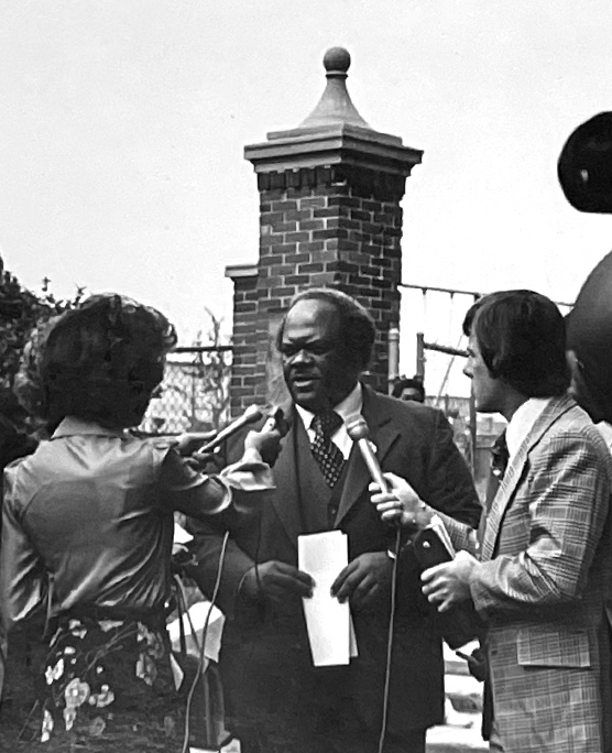 Archival photo of an Urban League leader speaking to reporters outdoors, holding papers at a press conference
